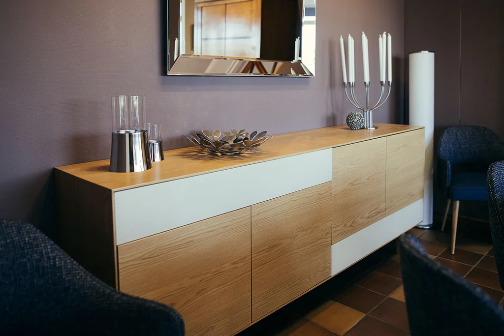 Un buffet dans une salle à manger avec des chaises et un miroir.